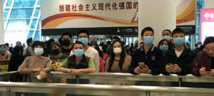 Noticias ONU/Jing Zhang: Gente con mascarillas espera en la zona de llegadas del aeropuerto internacional de Shenzhen Bao'an